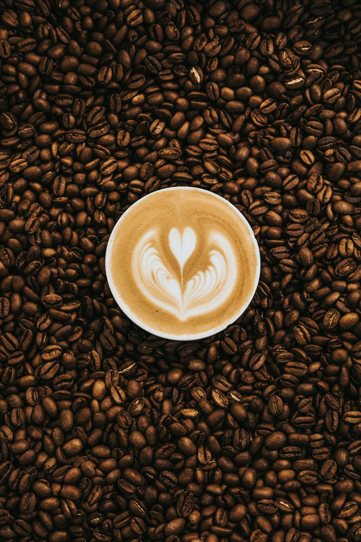Latte art on a cup of coffee, set on a bed of roasted beans