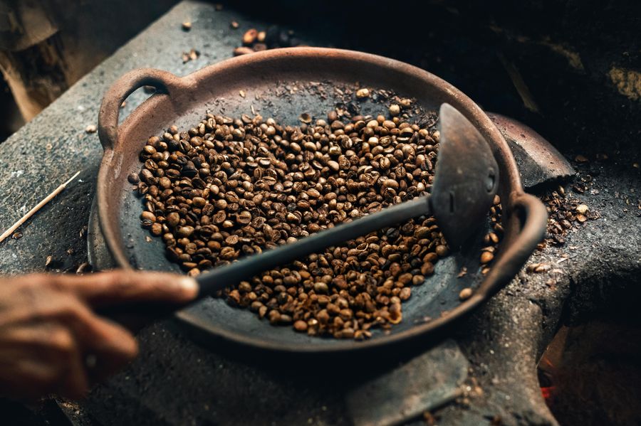 Coffee beans being hand-roasted in a traditional pan